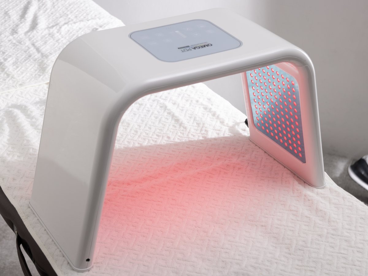 業務用LED美容機器 OMEGA PDT の本体が、赤色のLEDを照射している様子
